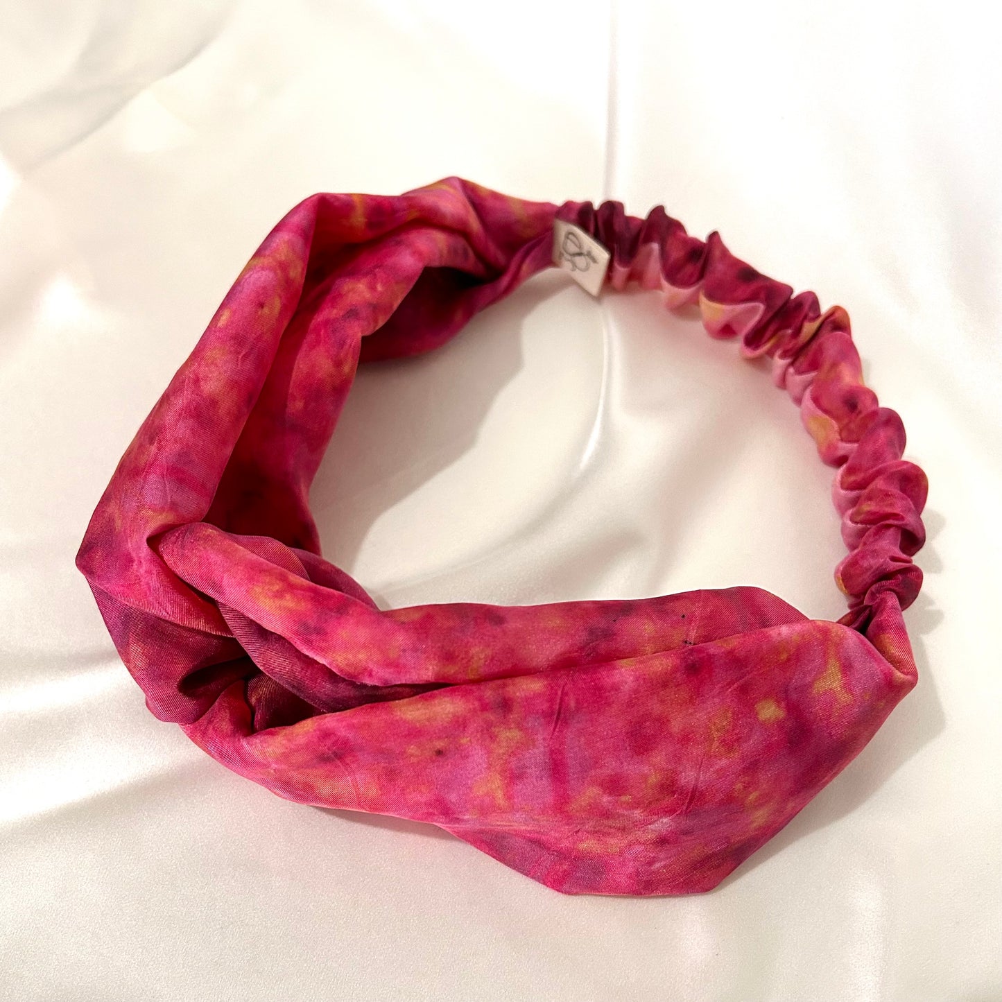 Bright pink silk turban headband with elastic to secure over head which has been naturally dyed with marigolds and chamomile flowers