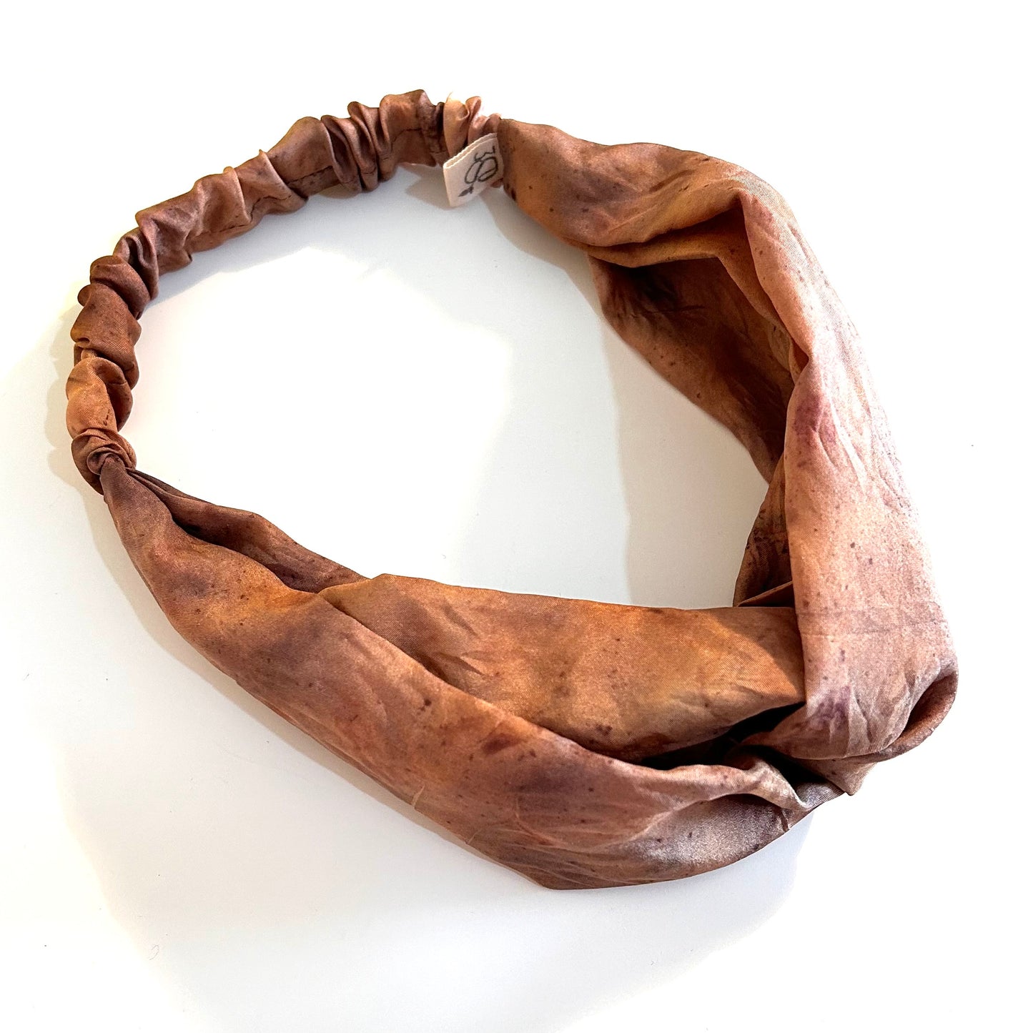 Brown silk turban headband with elastic to secure over head which has been naturally dyed with orange cosmos and yellow marigold flowers which are very subtle against the brown base