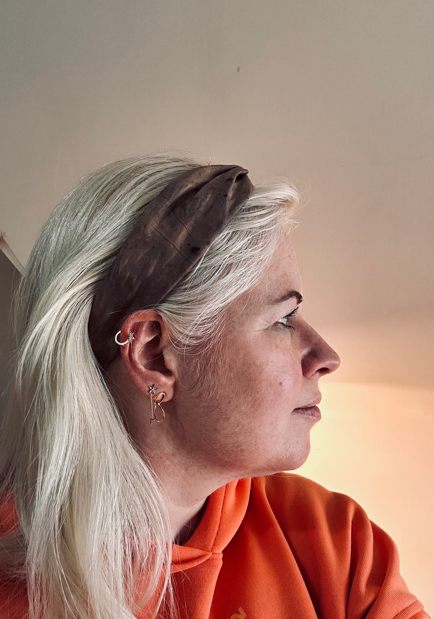 Headshot model wearing the brown silk turban headband and orange hoody