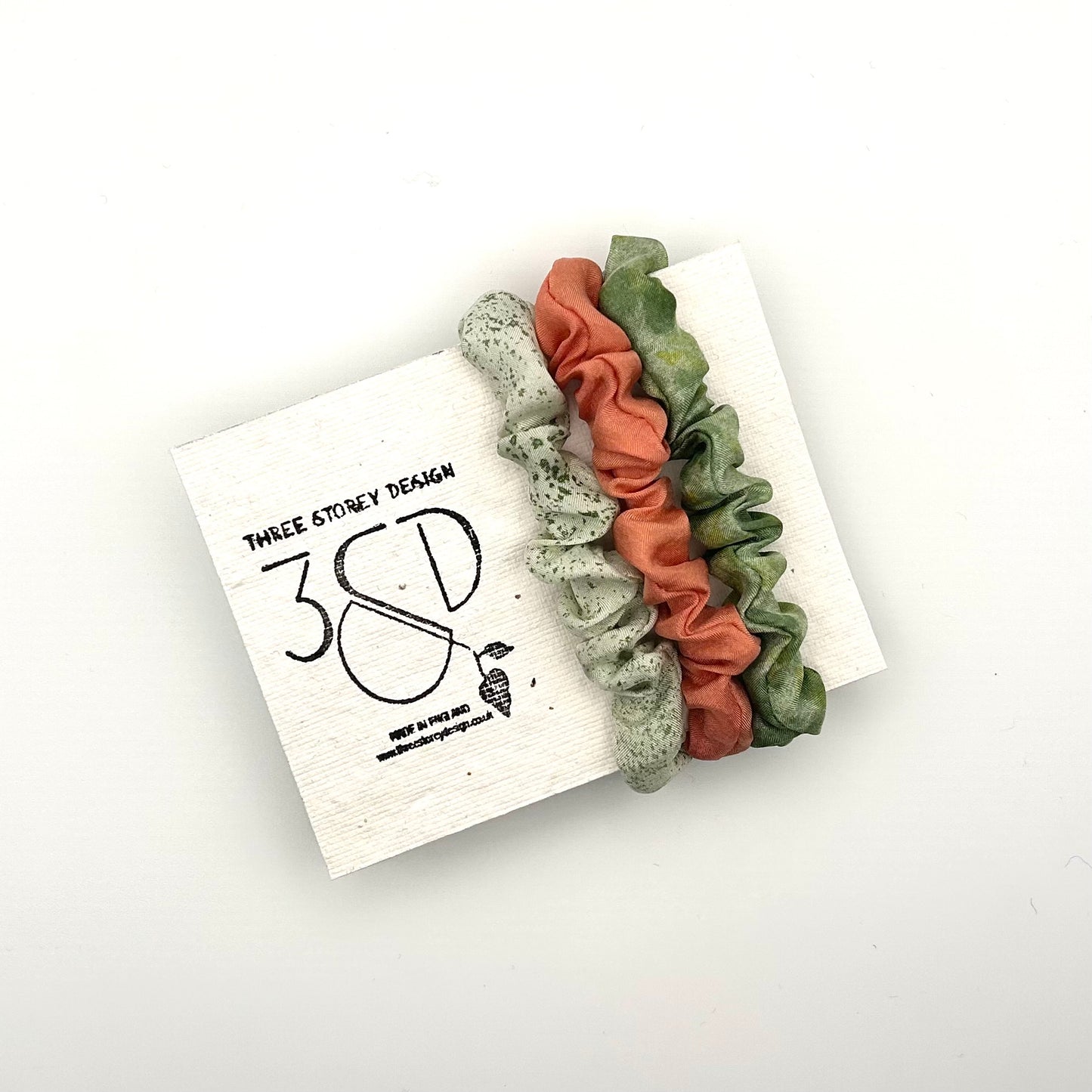 Pale green, Peach and Green naturally dyed 3 pack mini silk scrunchies presented on plantable branded packaging