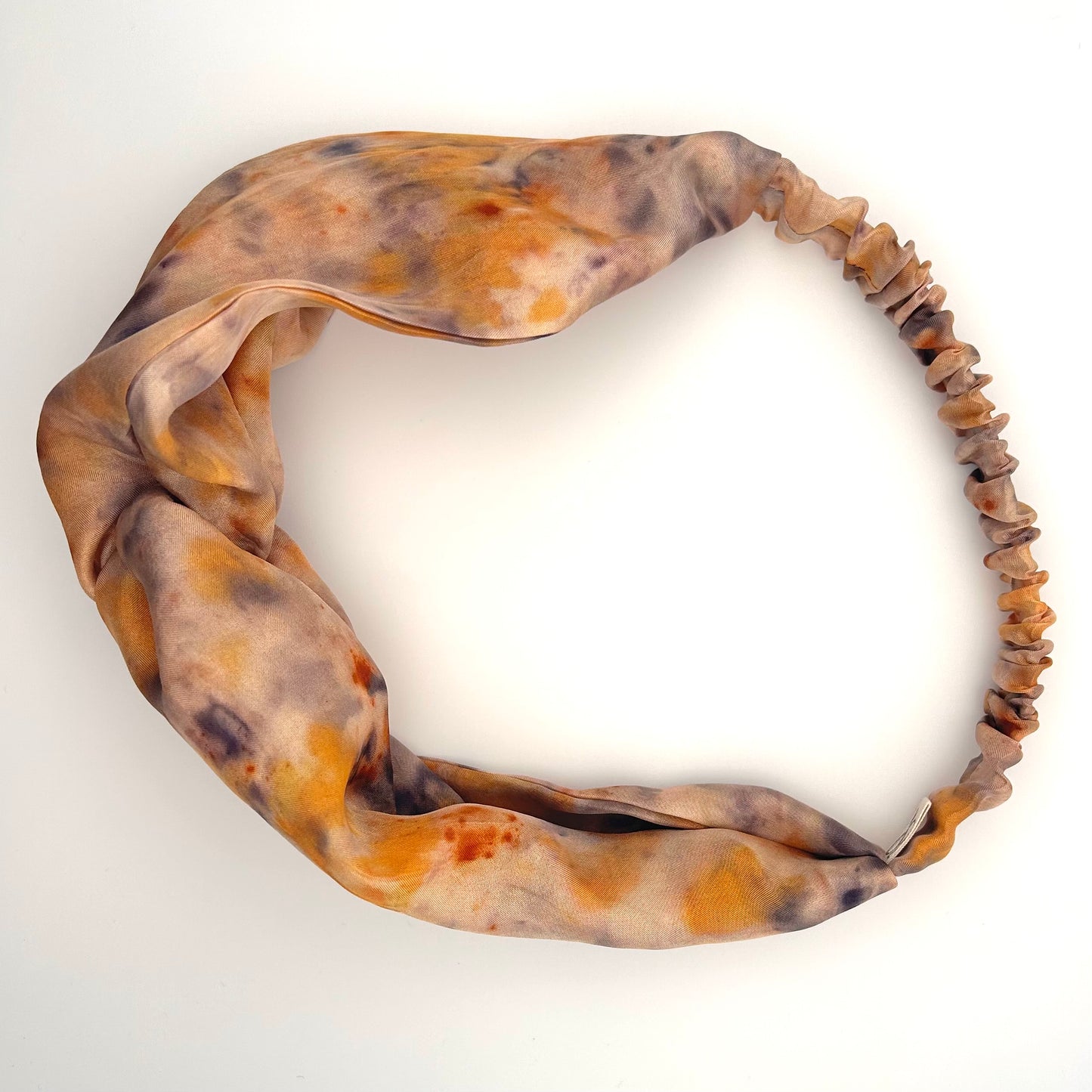 Peach silk turban headband with elastic to secure over head which has been naturally dyed with orange cosmos flowers and black beans