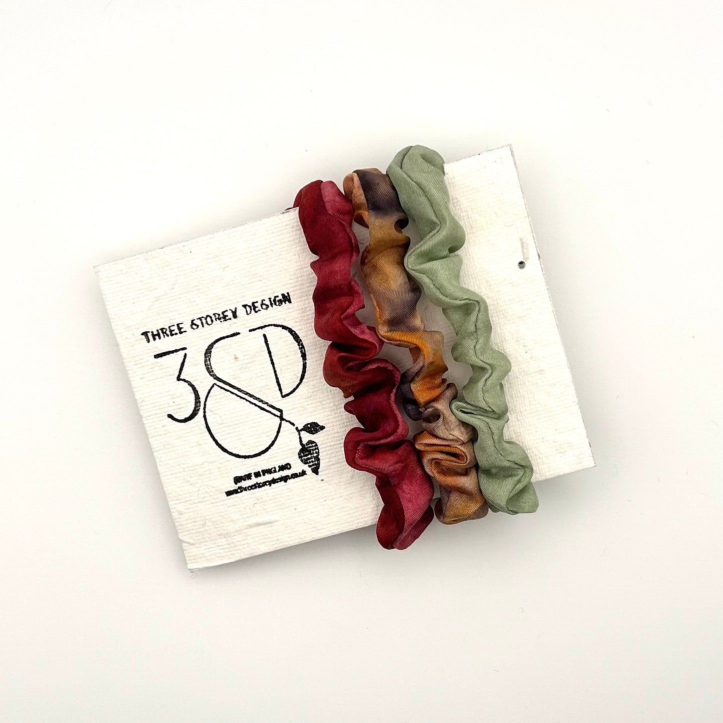 Red , Camel and Green naturally dyed 3 pack mini silk scrunchies presented on plantable branded packaging