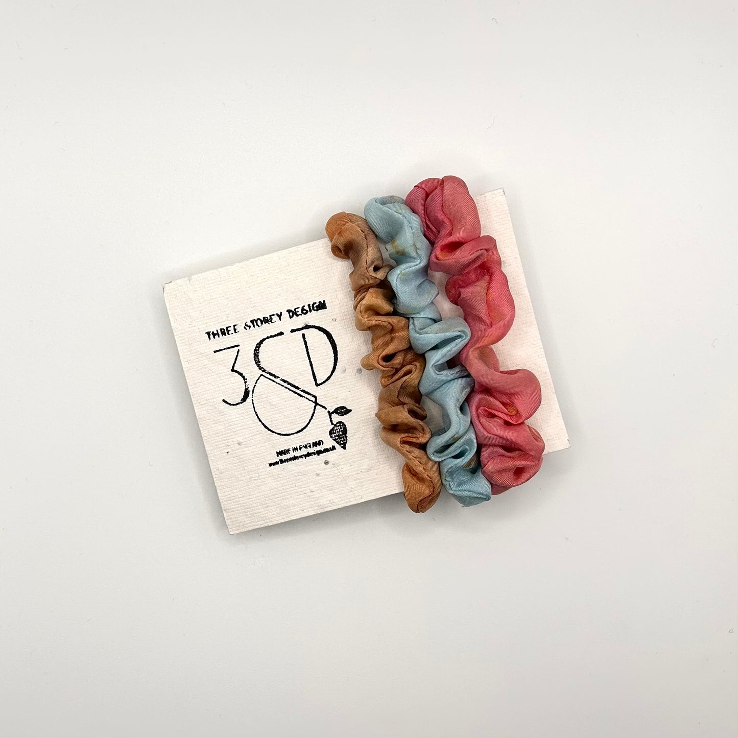 Camel , Blue and Pink naturally dyed 3 pack mini silk scrunchies presented on plantable branded packaging
