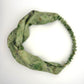 Green silk turban headband with elastic to secure over head which has been naturally dyed with purple pansy flowers
