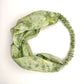Green silk turban headband with elastic to secure over head which has been naturally dyed with yellow marigolds flowers and sprayed green pattern