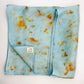 Pale indigo long silk scarf with naturally dyed hand-painted orange cosmos print  showing scarf folded into a square