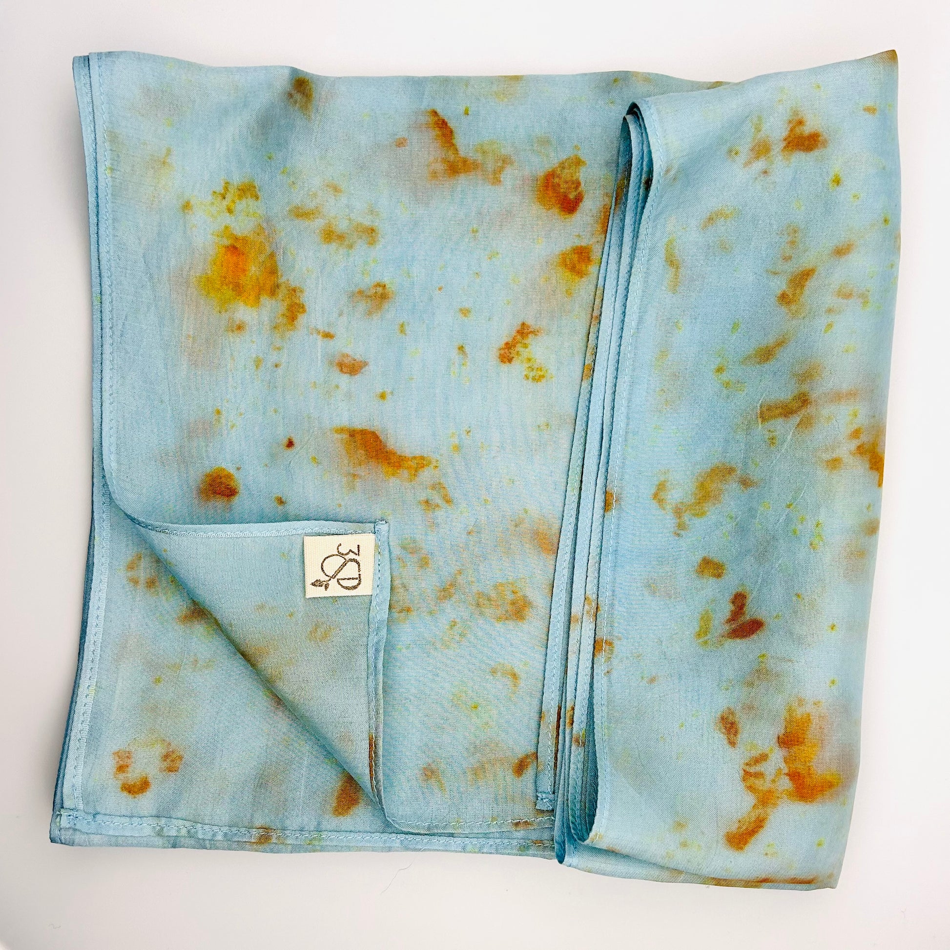 Pale indigo long silk scarf with naturally dyed hand-painted orange cosmos print  showing scarf folded into a square