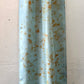 Pale indigo long silk scarf with orange cosmos naturally dyed print displayed on a hanger showing half the length