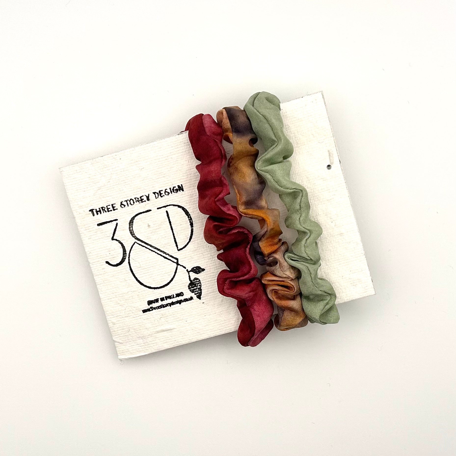 Red , Camel and Green naturally dyed 3 pack mini silk scrunchies presented on plantable branded packaging